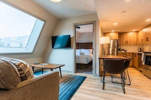 Relax in a spacious living area with a sofa and flat-screen TV, and enjoy a meal at the dining table near the kitchen.