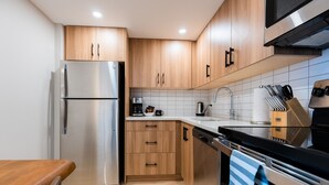 A modern kitchen with wooden cabinets, stainless steel appliances, and a tiled backsplash. - Superior Two Bedroom Apartment (Banff)