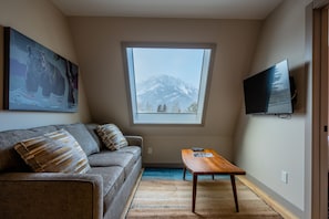 Enjoy a serene mountain view from the large window, with a flat-screen TV and comfortable sofa for relaxation.