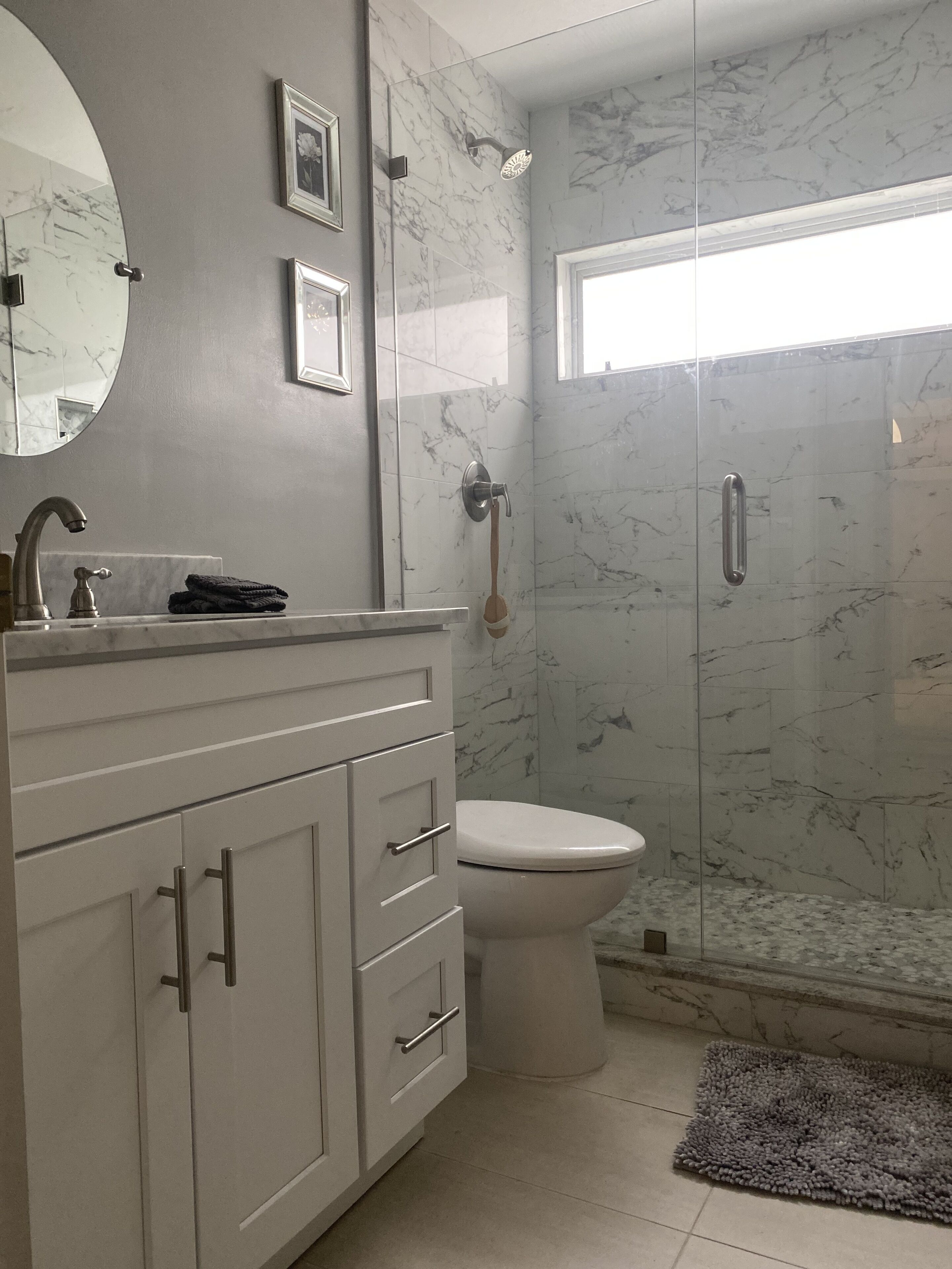 Een badkamer met een marmeren douche, toilet en een wastafel met lades.