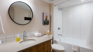 A modern bathroom with a round mirror, a sink, a toilet, and a bathtub. - Superior King Two Bedroom Apartment (Banff)