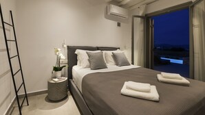 Una camera da letto moderna con un letto grande, un comodino con una pianta e vista sull'esterno attraverso una grande finestra.