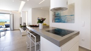 Una cucina moderna con un'isola grande, un'area pranzo con vista e un'opera d'arte contemporanea appesa al muro.
