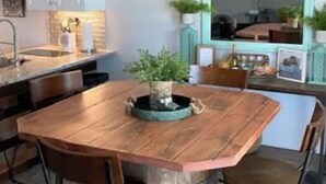 Une cuisine moderne avec un îlot central en bois, des tabourets de bar et des meubles blancs.
