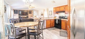 A modern kitchen with a central island, wooden cabinets, and a stainless steel refrigerator.