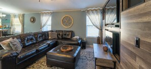 A living room with a leather sofa, ottoman, and a small wooden table with a football.