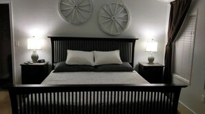 A bed with a headboard, two bedside tables with lamps, and decorative wall plates.