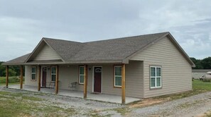 A single-story house with a gabled roof, a covered porch, and a front door.