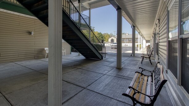 A covered outdoor area with a staircase, benches, and a clear view of the street.