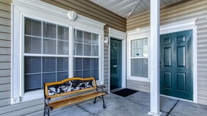 A porch with a bench, a green door, and a window with blinds.