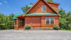 A log cabin with a green roof, a front porch, and a stone foundation. - Ern824 - Best Days - Great Location! Close To Town! 2 Bedroom Cabin by RedAwning (Pigeon Forge)
