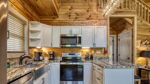 A modern kitchen with white cabinets, stainless steel appliances, and a wooden ceiling. - Ern824 - Best Days - Great Location! Close To Town! 2 Bedroom Cabin by RedAwning (Pigeon Forge)