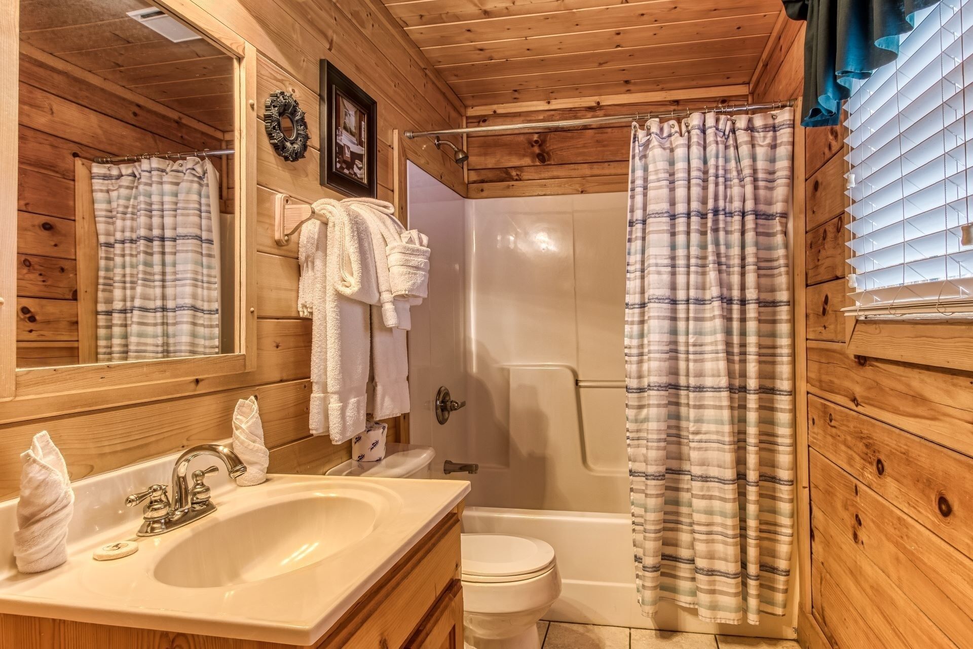 Une salle de bain rustique, aménagée dans une cabane en bois, avec un lavabo, des toilettes et une douche.