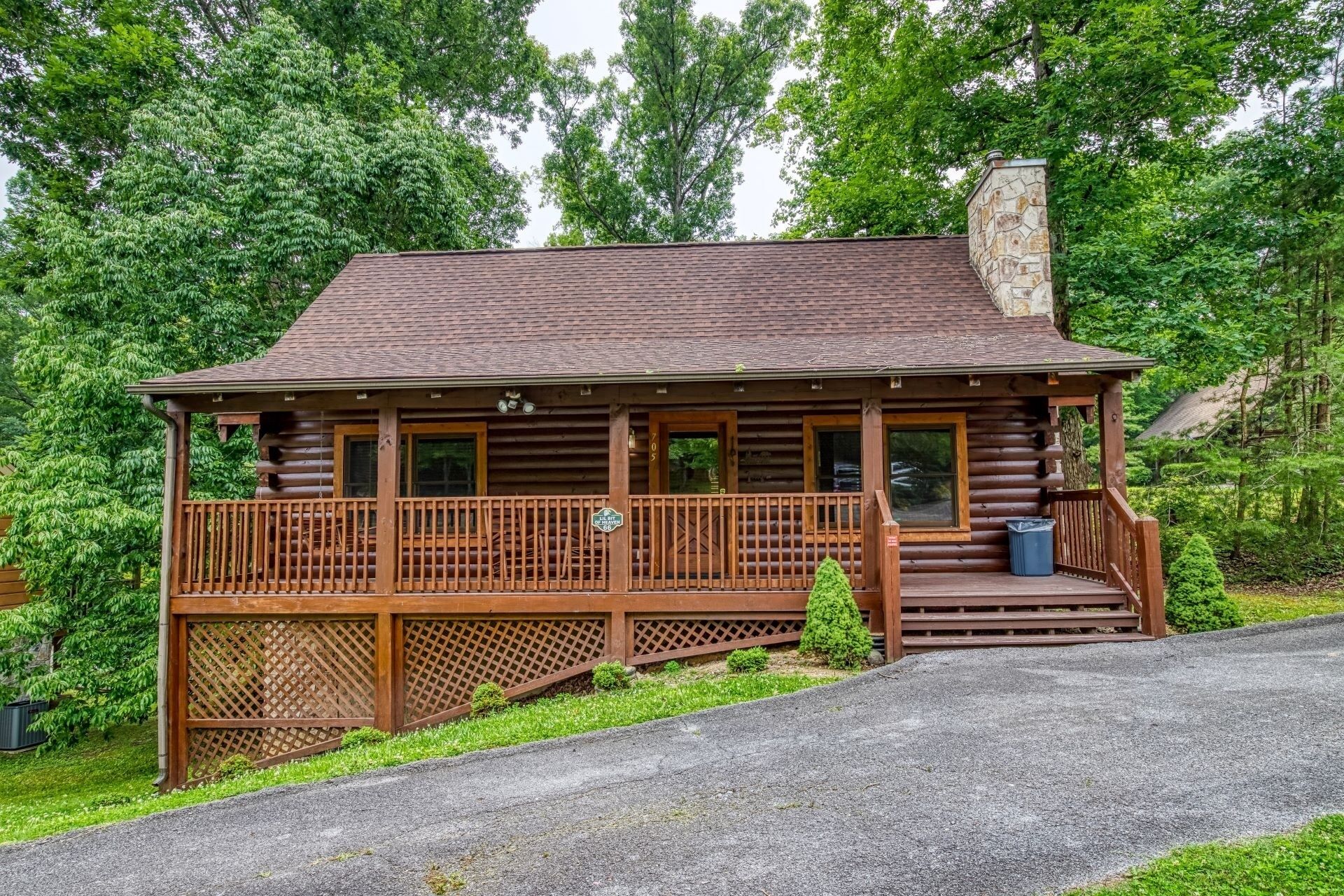 A log cabin with a porch, a chimney, and a small garden area.