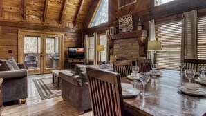 Interior acogedor de una cabaña con comedor, chimenea y televisor.