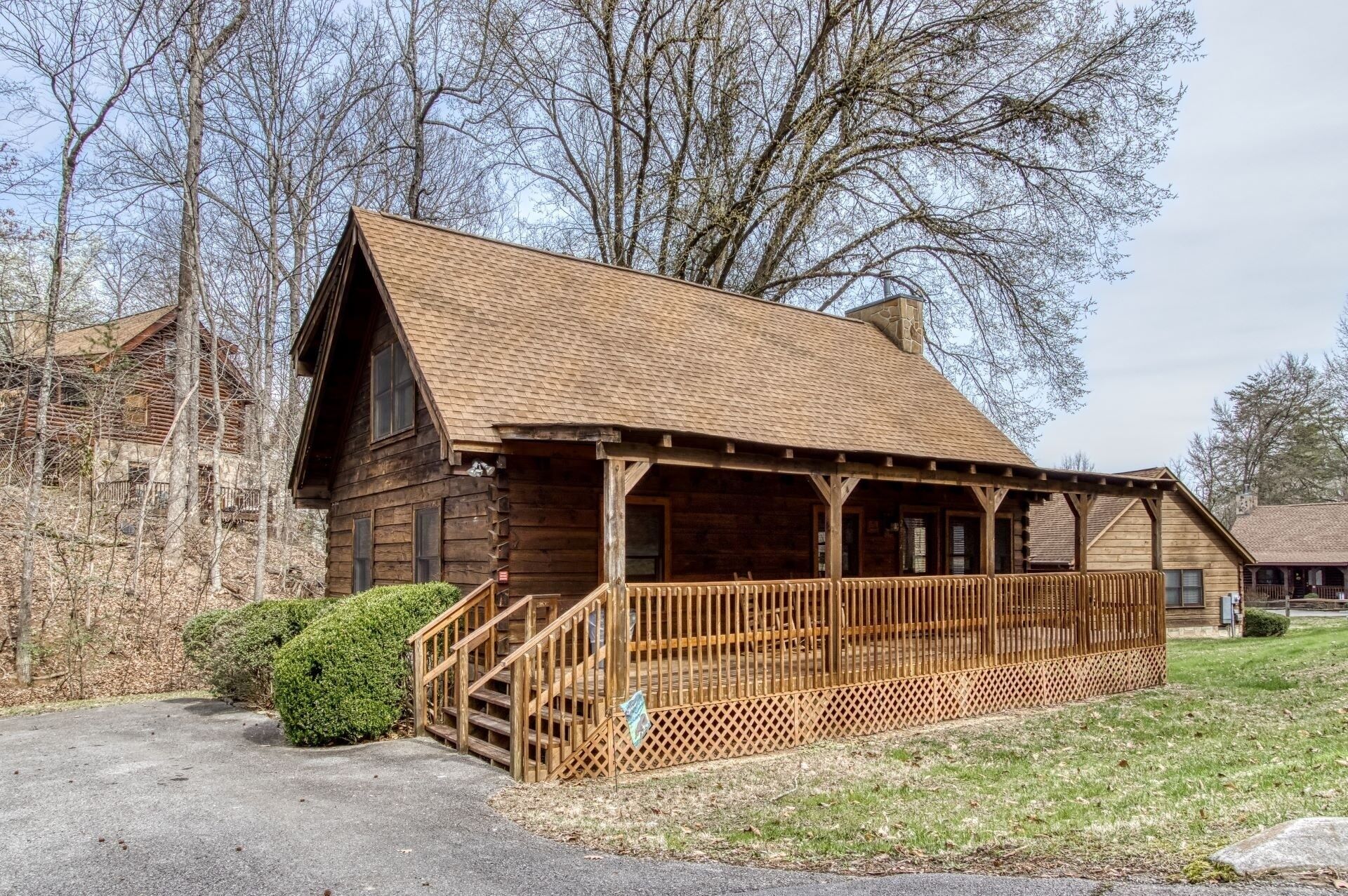 A rustic log cabin with a porch and a staircase leading to the entrance.