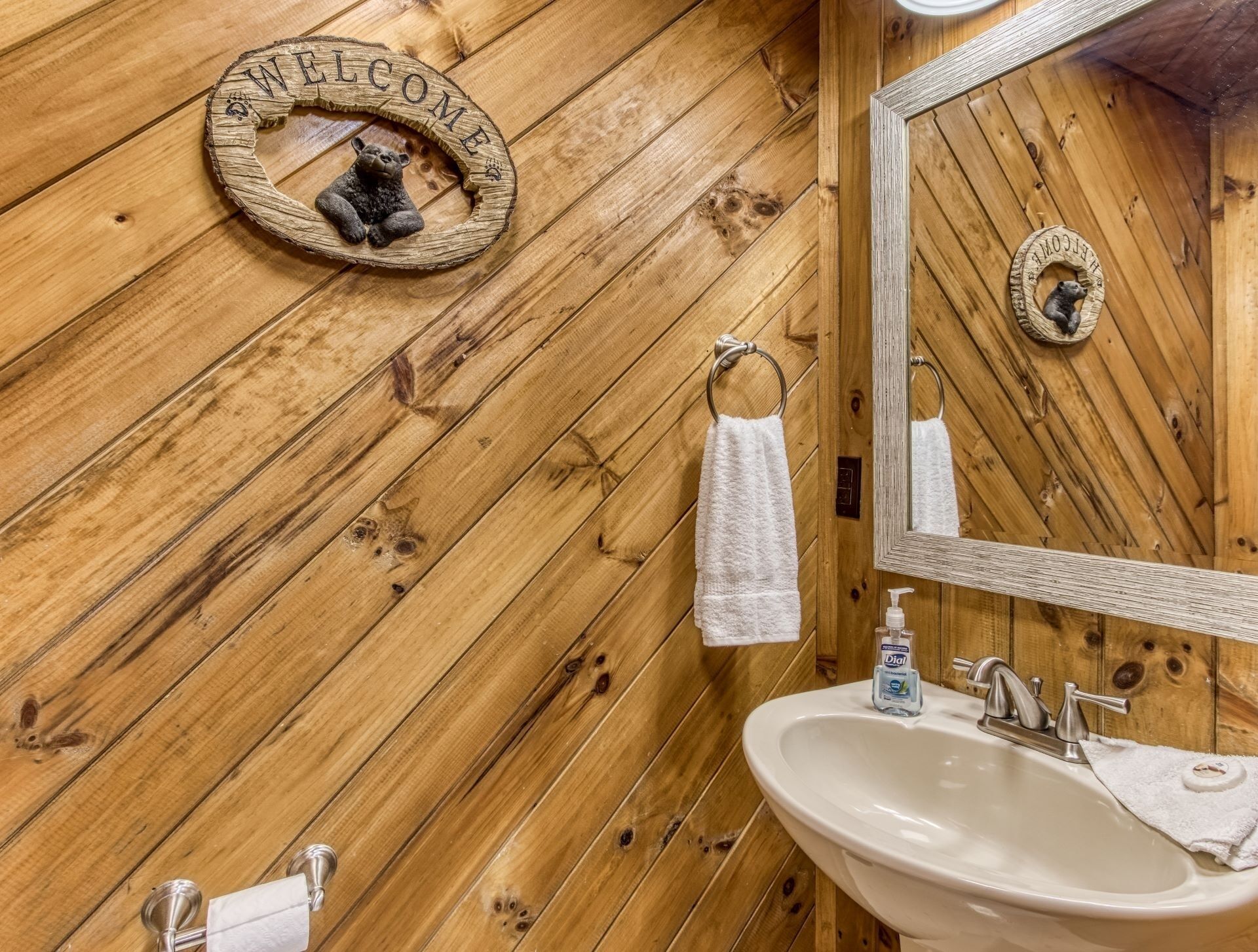 A wooden wall with a welcome sign and a mirror.