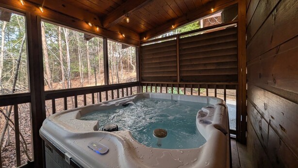 A hot tub in a wooden cabin with a view of a forest. - ER245 - Almost Heaven Great Location - Close To Town! 3 Bedroom Cabin by RedAwning (Pigeon Forge)