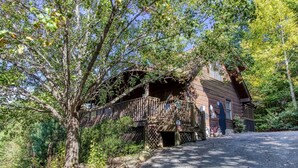 A rustic wooden building with a covered porch and a stone pathway leading to it. - ER245 - Almost Heaven Great Location - Close To Town! 3 Bedroom Cabin by RedAwning (Pigeon Forge)