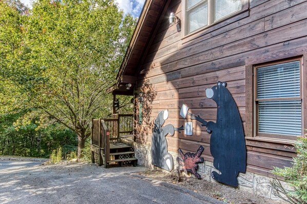 En rustik træhytte med et bjørnemaleri på væggen, en veranda og en stensokkel.