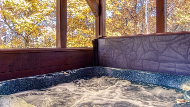 Un bain à remous avec vue sur les arbres aux couleurs automnales, grâce à de grandes fenêtres.