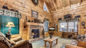 A cozy cabin interior with a stone fireplace, wooden walls, and rustic decor. - Er84 - Serenity Summit - Great Location. Close To All The Action! 1 Bedroom Cabin by RedAwning (Pigeon Forge)