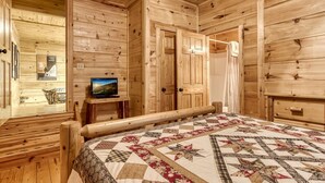 Ein Zimmer in einer Holzhütte mit einem Bett, einem Fernseher auf einem kleinen Tisch und einem Poster an der Wand.