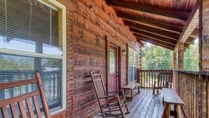 Eine hölzerne Veranda mit Schaukelstühlen und einer Bank, überdacht mit einem Holzdach.