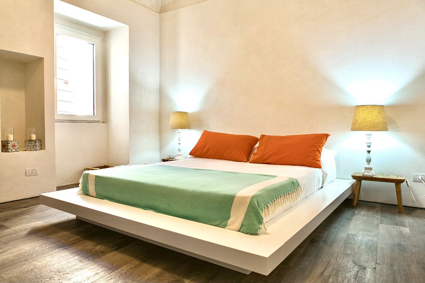 Un dormitorio moderno con una cama grande, dos mesitas de noche y una ventana.