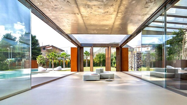 A modern interior with a glass wall, a pool, and outdoor seating.