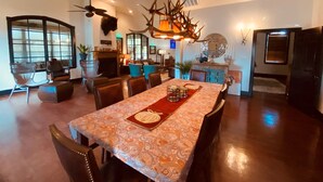 A spacious dining area with a large table, chairs, and a chandelier. - Happy Trails Cowboy Cabin HOT TUB POOL on 12 ac (Bandera)