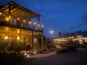 Een gebouw met twee verdiepingen, een overdekt terras, een gevel van natuursteen en lichtjes.