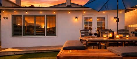 A patio with a wooden table and chairs, a blue umbrella, and candles.