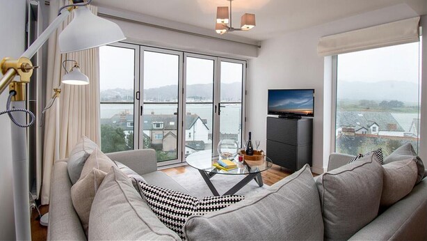 A modern living room with a sofa, a glass table, and a TV.