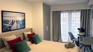 A hotel room with a large bed, a desk with two chairs, a window with curtains, and a framed picture on the wall. - Studio Seafront Promenade des Anglais (Nice)