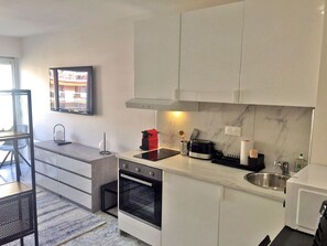 A modern kitchen with white cabinets, a built-in oven, a microwave, and a sink.