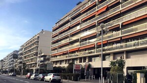 A multi-story building with a series of balconies, a sign for AVIA, and parked cars along the street. - Studio Seafront Promenade des Anglais (Nice)