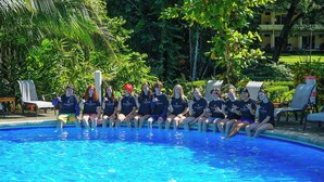 A group of people sitting by a pool with lounge chairs and greenery in the background. - Blue Horizon one bedroom apartment B Quepos Complimentary access to Beach Club (Quepos)