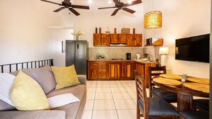 A modern kitchen with wooden cabinets, a dining area with a round table and chairs, a built-in oven, and a ceiling fan. - Blue Horizon one bedroom apartment B Quepos Complimentary access to Beach Club (Quepos)