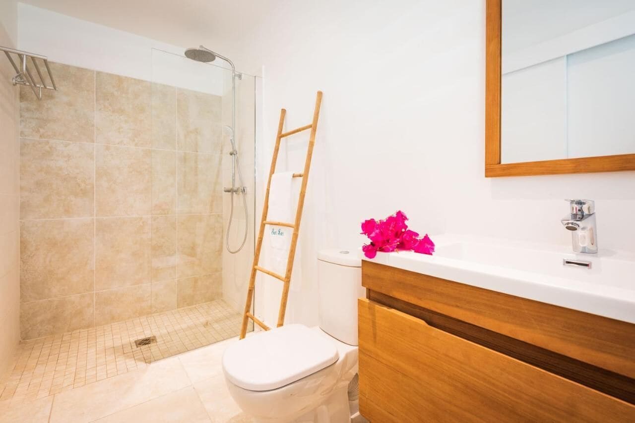 Un baño con ducha, inodoro y tocador.