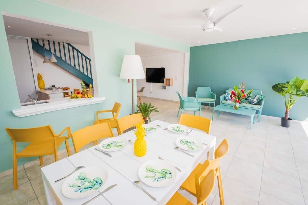 A dining area with a table set for four, yellow chairs, and a pineapple centerpiece.