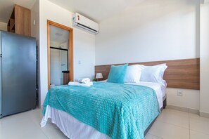 A hotel room with a bed, a wardrobe, and an air conditioning unit.