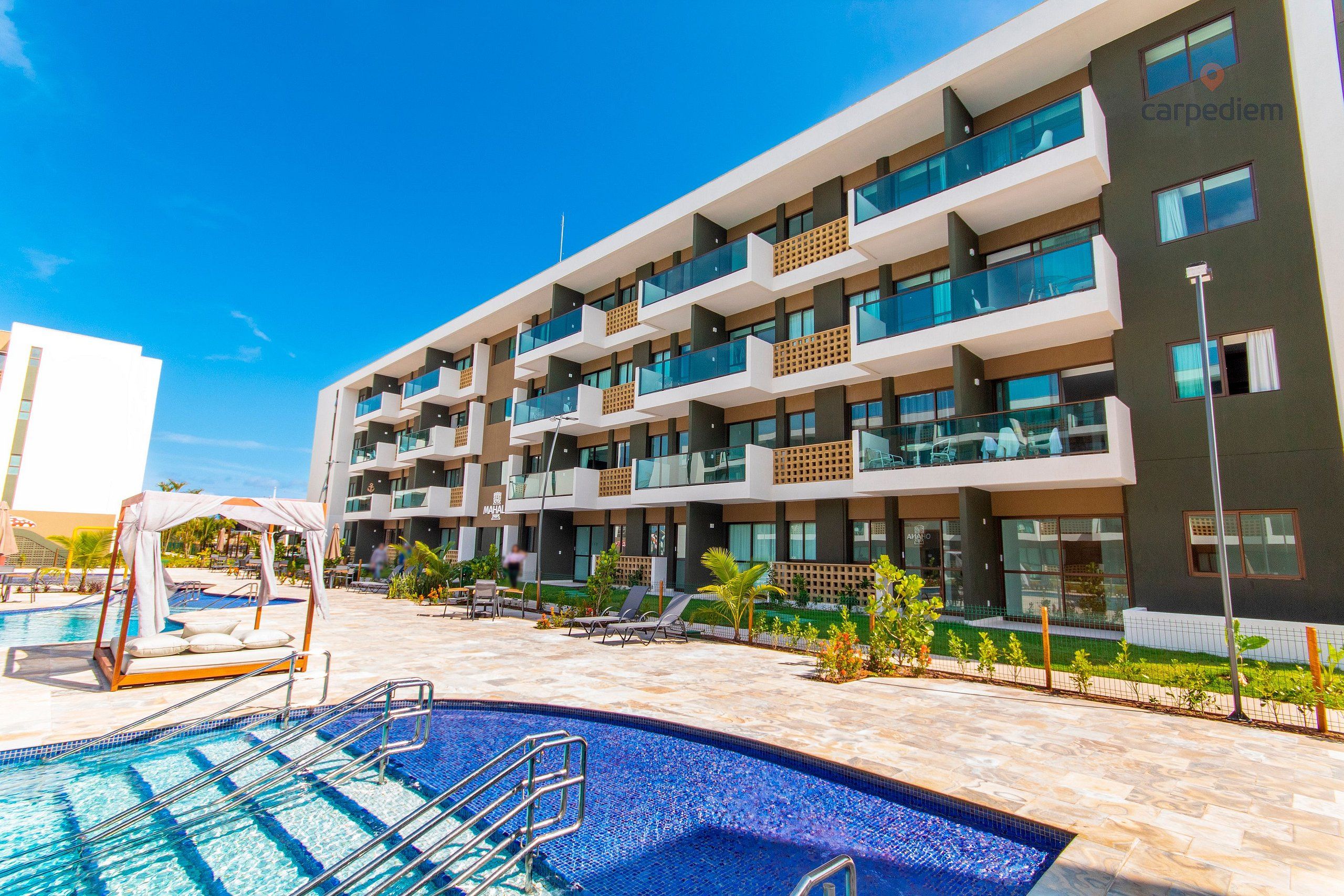 A modern hotel with a swimming pool, multiple balconies, and a well-maintained outdoor area.