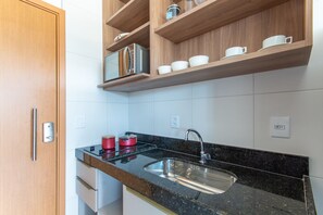 A modern kitchen with wooden cabinets, a stainless steel sink, and a black granite countertop. - Mana Beach Experience B16 - Carpediem (Ipojuca)