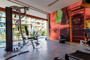 A gym with exercise equipment, a treadmill, and a view of a residential building.