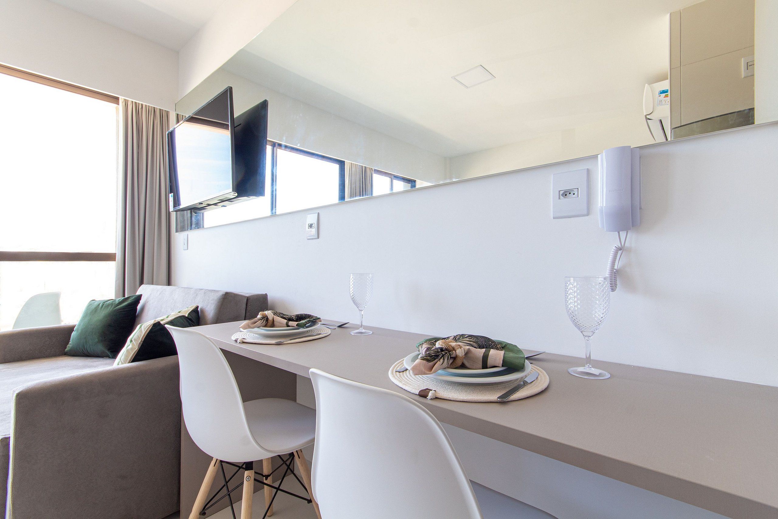 Uma sala de jantar moderna com uma mesa comprida, cadeiras brancas e um sofá.