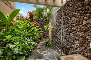 Relax by the soothing water feature surrounded by lush tropical plants and a stone wall.