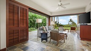 Une vaste terrasse dotée d’un canapé, de fauteuils et d’un téléviseur.