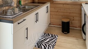 Cocina de cabaña de madera con techo de madera, un reloj en la pared, un lavamanos y una ventana con cortinas.
