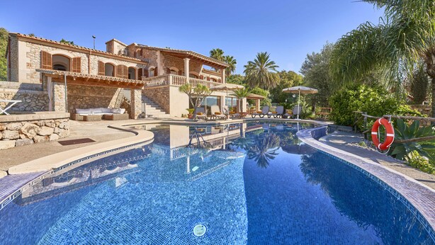 A poolside area with a stone building, lounge chairs, and a lifebuoy. - Villa in Búger perfect for children with swimming pool, paddle court and large garden (Búger)